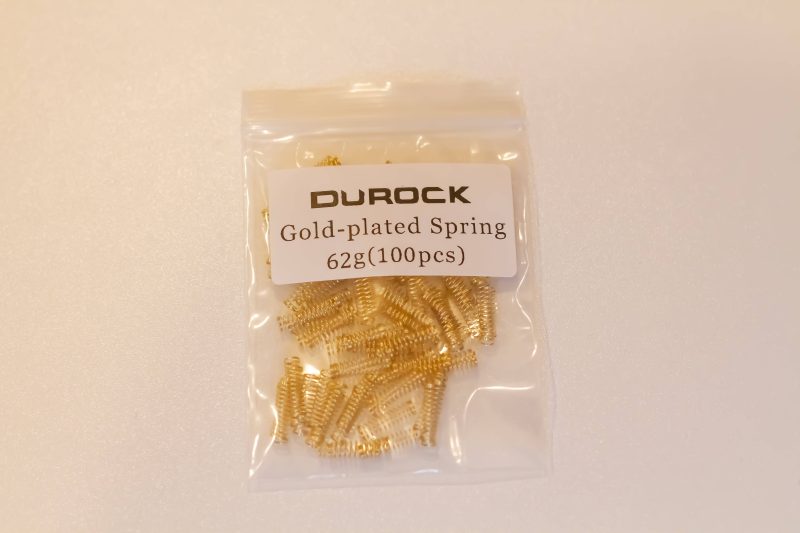 A pack of one hundred gold plated Durock mechanical switch springs with 62 grams of bottom out weight.