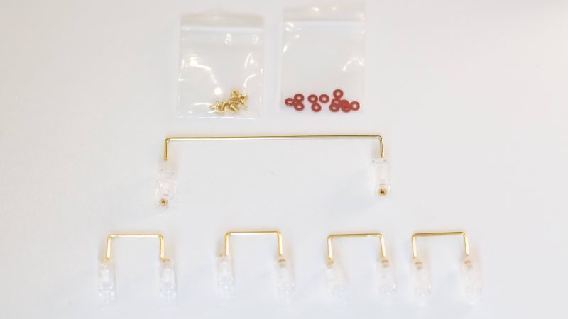 Clear Durock V2 stabilizers with gold wires, gold screws, and red screw dampener pads for DIY mechanical keyboards..